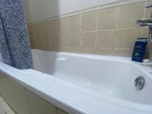 a white bath tub in a bathroom with a shower curtain at Comfort Bed Inn in Dubai