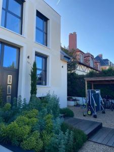 une maison blanche avec un jardin en face dans l'établissement Location maison Versailles piscine -5 chambres, à Versailles