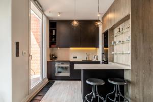 a kitchen with black cabinets and bar stools at YOURAPART Rajska City Centre in Gdańsk