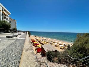 a beach with chairs and umbrellas and the ocean at Apartamento Vista Mar a menos de 50m da praia. in Armação de Pêra +8 photos