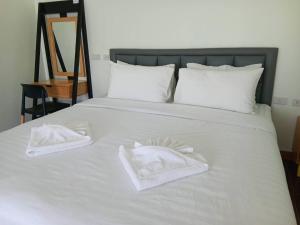 een wit bed met twee witte handdoeken erop bij โรงแรมนราพัตรา in Narathiwat
