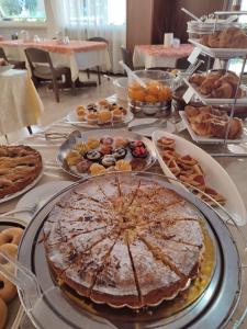 una tavola con torte, prodotti da forno e altri prodotti alimentari di Albergo Villa Mimosa a Torbole