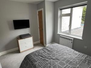 a bedroom with a bed and a tv and a window at New 2 bedroom first floor apartment close to beach in Southbourne