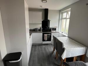 kuchnia z białymi szafkami, stołem i oknem w obiekcie New 2 bedroom first floor apartment close to beach w mieście Southbourne