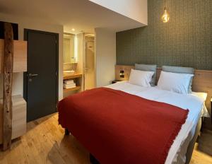 1 dormitorio con 1 cama grande con manta roja en B&B Les Oiseaux de Passage, en Harre