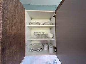 a cupboard with plates and dishes in a kitchen at Appart Cosy tt confort - Sceaux - 20mn de Paris in Sceaux