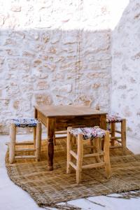 a wooden table and two stools in front of a wall at Villa Madame Babouche, chambre Tanirt, SdB privative in Oulad el Madani