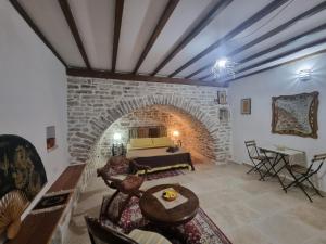 ケパロにあるVilla Olive Old Qeparoの石造りの暖炉とテーブル付きのリビングルーム
