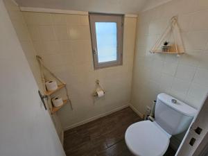 a bathroom with a white toilet and a window at Maisonnette du Relais de Vauchamps 