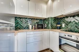 - une cuisine avec des placards blancs et des murs carrelés verts dans l'établissement Le Gentleman - Design & Lumineux - Business, à Paris