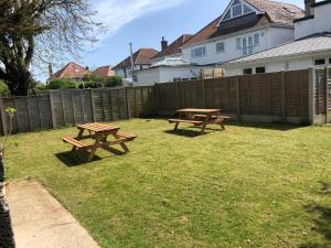 two picnic tables in a yard next to a fence at 1 bedroom ground floor apartment in Southbourne
