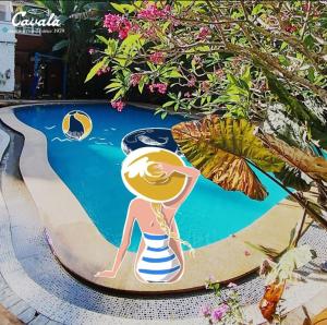 a painting of a woman on a surfboard in a pool at Cavala The Seaside Resort in Baga