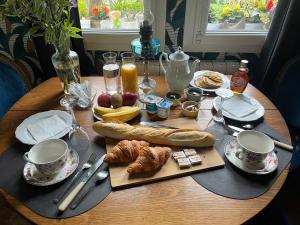 una mesa de madera con alimentos para el desayuno y bebidas. en Chambre cosy, 