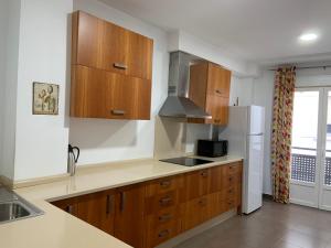 Una cocina con gabinetes de madera y refrigerador. en APARTAMENTO JALAMA 1B, en Moraleja