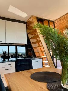 una cocina y una escalera en una casa con mesa en Stodoła Na Kresach - widokowy domek drewniany, całoroczny JACUZZI & SAUNA en Bodzentyn