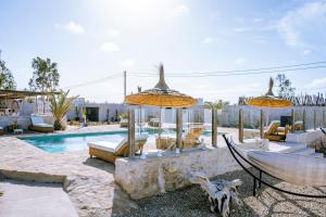 a pool with chairs and umbrellas in a yard at Villa Madame Babouche, Studio Lahna, SdB privative in Oulad el Madani