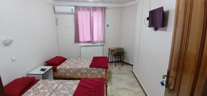Cette petite chambre comprend 2 lits et une télévision. dans l'établissement Hostel 1 er novembre khenchela, à Khenchela