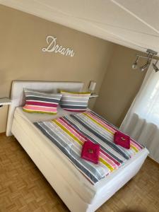 Una cama blanca con almohadas coloridas encima. en Schrammi's Ferienwohnung, en Schwanau