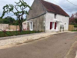 una casa blanca con persianas rojas en una calle en Le gîte du Tremblay, en Étais-la-Sauvin