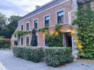 um edifício de tijolos com arbustos à frente em B&B Les Oiseaux de Passage em Harre