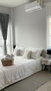 a white bed with white pillows and a basket on it at House near the beach in Nai Yang Beach