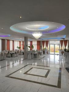 a large banquet hall with white tables and a chandelier at Hotel Praga in Gorno Lakočerej