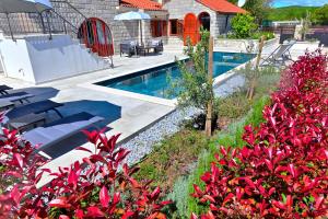 a swimming pool in a yard with red flowers at Vacation house Rubi in Dubrovnik
