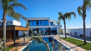 a house with a swimming pool and palm trees at Alfa Villa in Rrushkull