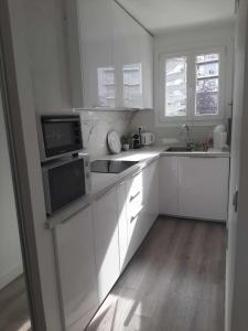 uma cozinha branca com armários e electrodomésticos brancos em Magnifique Studio de 25 m2 em Paris