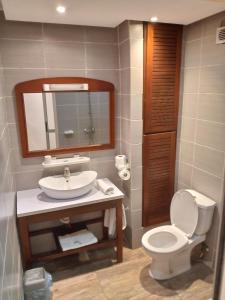 W łazience znajduje się toaleta, umywalka i lustro. w obiekcie Bau rivage hotel w mieście Akwa