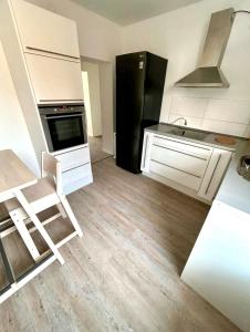 a kitchen with a black refrigerator and white cabinets at Interior Apartments in Kassel Bad Wilhelmshöhe in Kassel