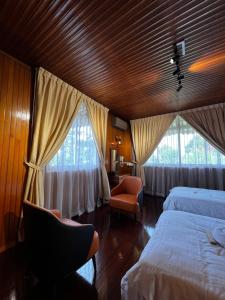 a bedroom with two beds and a chair and two windows at 3 Retro-Antique Inspired Interconnected Family Rooms at Country Lodge - Eco Valley Retreat 豐之谷 in Tawau