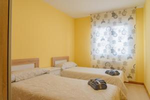 - 2 lits dans une chambre aux murs jaunes dans l'établissement CASA CHARROS, à Saragosse
