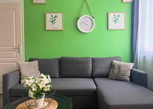 a living room with a couch and a clock on a green wall at Apart'Moment Saint-Omer Centre in Saint-Omer