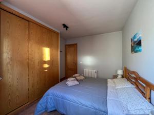 1 dormitorio con 1 cama azul y armario de madera en La Vall Apartaments Loft, en Sant Llorenç de Morunys