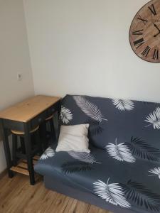 a blue couch sitting next to a table with a clock at Studio en plein cœur d’aubusson in Aubusson