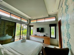 a bedroom with a bed and a tv and windows at ProudChan Boutique Resort in Chanthaburi