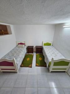 two beds in a room with rugs on the floor at Hadhri Appartement in Tozeur