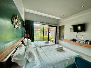 een slaapkamer met 2 bedden en een groot raam bij ProudChan Boutique Resort in Chanthaburi