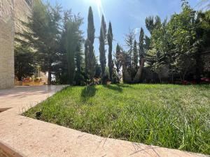 une cour avec des arbres et de l'herbe et un trottoir dans l'établissement Horizon1, à Amman