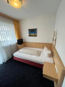 een kleine slaapkamer met een bed en een televisie bij Hotel-Landpension Postwirt in Kirchensittenbach