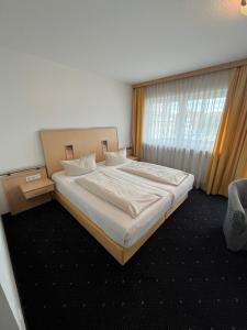 een slaapkamer met een groot bed met witte lakens en een raam bij Hotel-Landpension Postwirt in Kirchensittenbach
