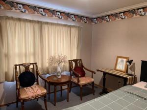 um quarto com uma cama e cadeiras, uma mesa e um piano em Riverdale Ensuite em Palmerston North