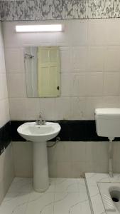 a bathroom with a sink and a mirror and a toilet at Hotel Flower of Capital in Islamabad