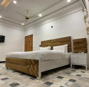 a bedroom with a large bed with a wooden headboard at Hotel Flower of Capital in Islamabad