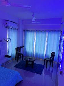 1 dormitorio con iluminación azul, mesa y sillas en Pearl villa homestay, en Jorhāt