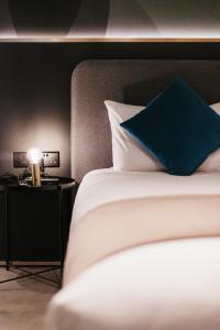 a bed with a blue pillow on top of it at Eleven by Warren Collection in Sliema
