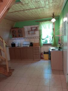 a kitchen with green walls and wooden cabinets and a window at Domki nad potokiem w Baligrodzie in Baligród
