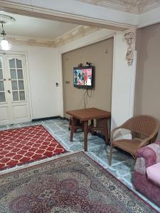 een woonkamer met een tafel en een tv aan de muur bij Room in Al Bitash Main Street, Alex west in Alexandrië