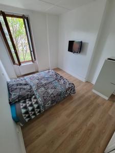 a bedroom with a bed and a tv on the wall at Chambres spacieuses hyper centre in Saint-Étienne